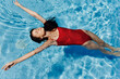 © SHOTPRIME STUDIO - Happy woman swimming in the pool in red swimsuit with loose long hair relaxed in the sunshine, skin protection with sunscreen, concept of relaxing on vacation in tropical climate, lifestyle.