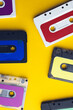 Overhead view of six colourful cassette tapes on yellow background