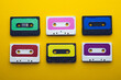 Overhead view of six colourful cassette tapes arranged on yellow background