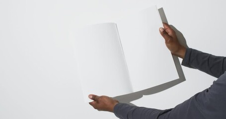 Wall Mural - Video of hand of african american man holding book with blank pages, copy space on white background