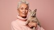 A charming duo against a pastel studio backdrop – senior woman and her cat.
