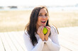 © luismolinero - Middle aged woman holding an apple with surprised expression