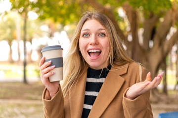 Wall Mural - Young pretty blonde woman holding a take away coffee at outdoors with shocked facial expression