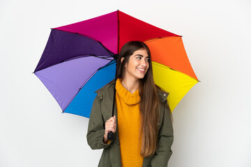 Young woman holding an umbrella isolated on white background looking to the side and smiling