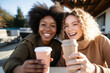 © ty - two female friends drinking coffee and taking selfies at a picnic table