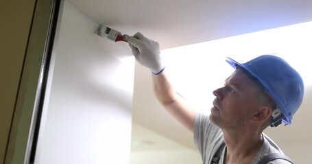 Wall Mural - Male builder painting wall white with brush 4k movie slow motion. Finishing work in apartments concept