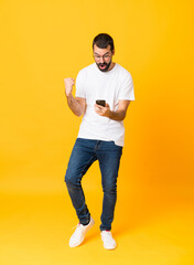 Wall Mural - Full-length shot of man with beard over isolated yellow background surprised and sending a message