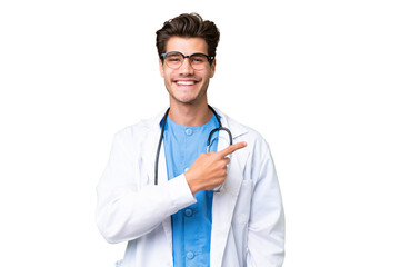 Wall Mural - Young doctor man over isolated background pointing to the side to present a product