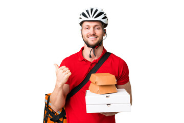 Wall Mural - Young delivery man taking a takeaway food over isolated chroma key background pointing to the side to present a product