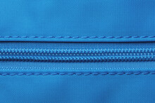 Zip Fastener Background Texture. A High-resolution Close-up Of A Detail From A Closed Plastic Zip Fastening On A Backpack Made Of An Elastic Blue Nylon Fabric. Macro Photo.