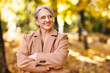 Happy positive mature woman with smile  in elegant clothes on an autumn walk in city park.