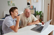© DragonImages - Grandfather and grandson watching video on laptop together