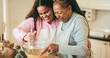 © DisobeyArt - African mother and daughter having fun preparing fruit cake at home - Winter holidays and family concept - Soft focus on senior woman mouth
