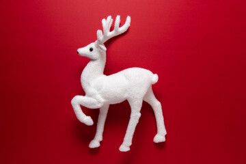 White reindeer on red background. Christmas or New Year minimal concept. Flat lay.