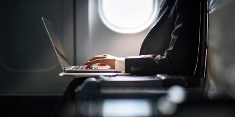 Successful Asian business woman, Business woman working in airplane cabin during flight on laptop computer