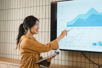 The female Chief Analyst is conducting a meeting presentation for a team of economists. The projector screen shows graphs, product sales, revenue growth strategies, and e-commerce analysis.