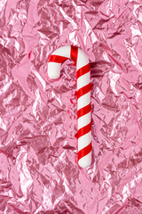 Wall Mural - Christmas candy on pink crumpled foil background. Minimal holiday concept.