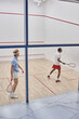 © LIGHTFIELD STUDIOS - multicultural friends in sportswear playing squash together inside of court, motivation and sport
