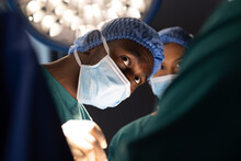 Diverse Male And Female Surgeons With Face Masks Doing Surgery In Hospital Operating Room