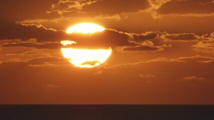 Wall Mural - beautiful evening sunset with big sun and clouds in the atlantic ocean at portugal coast.
