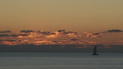 Wall Mural - beautiful evening sunset with clouds and a sailing yacht in the atlantic ocean on the coast of portu