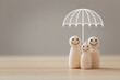 Family insurance and safety concept, Wooden figure with umbrella icon for protecting and care family.