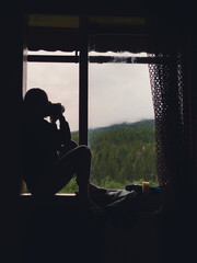 Wall Mural - woman near window looking at rainy mountains