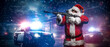 © Fxquadro - A man dressed as Santa Claus, aiming with a machine gun, poses in front of police cars with numerous police lights and sirens, amid a snowy stormy night on the street