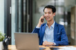 © amnaj - Asian businessman talking by smartphone in office. Smiling professional businessman manager talking on phone working communicating at work.