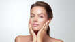 © UseeIvan - beautiful young woman lightly touching face with hands on white background, clean glowing skin