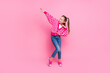 Portrait of cheerful girl with ponytails wear print sweater denim pants dancing look at sale empty space isolated on pink color background