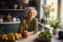 Smiling Middle Aged Woman Sitting In Domestic Kitchen At Home