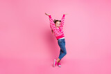 Fototapeta  - Portrait of overjoyed girl with fluttering ponytails wear print sweater denim pants raisng hands up isolated on pink color background