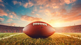 Fototapeta Sport - American football ball on green grass field with sunset sky background. Copy space.
