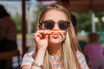 Teenage girl eating french fries and fooling around in an outside restaurant