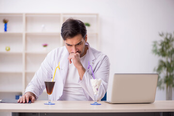 Wall Mural - Young male chemist examining soft drink at the lab