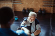 © Davor - Smiling senior man working out with assistance of personal trainer at gym