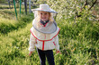 A little girl in a beekeeper costume helps in an apiary caring for bees