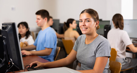 Canvas Print - Portrait of smiling girl student looking at camera during lesson in computer class in college