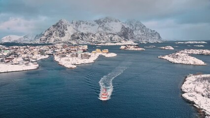 Wall Mural - aerial view of floating fishing boat in blue sea in snowy henningsvaer village, lofoten islands, nor