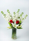 Fototapeta Psy - A vertical image of a beautiful bouquet of white delphinium, white lilies and red roses in a glass vase on isolated on white background