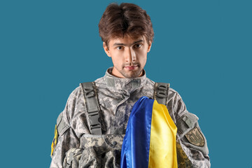 Wall Mural - Young male soldier with flag of Ukraine on blue background