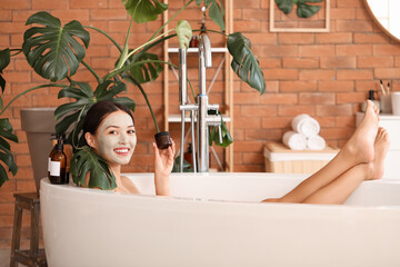 Sticker - Beautiful Asian woman with clay mask taking bath at home