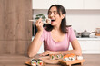 © Pixel-Shot - Happy young woman eating tasty sushi rolls in kitchen