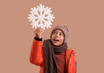 Poster - Little African-American boy in winter clothes with decorative snowflake on beige background