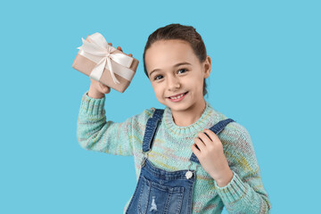 Wall Mural - Cute little girl with gift box on blue background