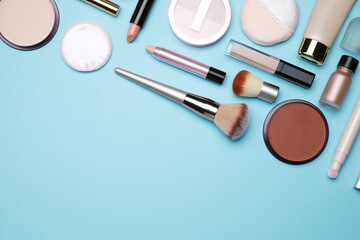 Wall Mural - Face powders and other decorative cosmetic products on light blue background, flat lay. Space for text