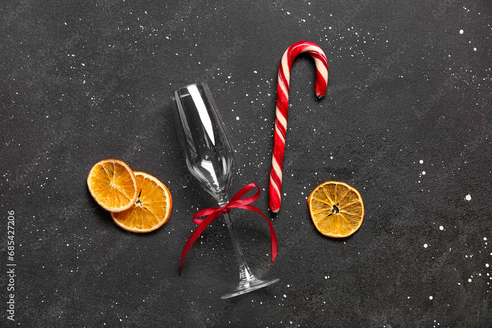 Dried orange slices with Christmas candy cane and glass on black background