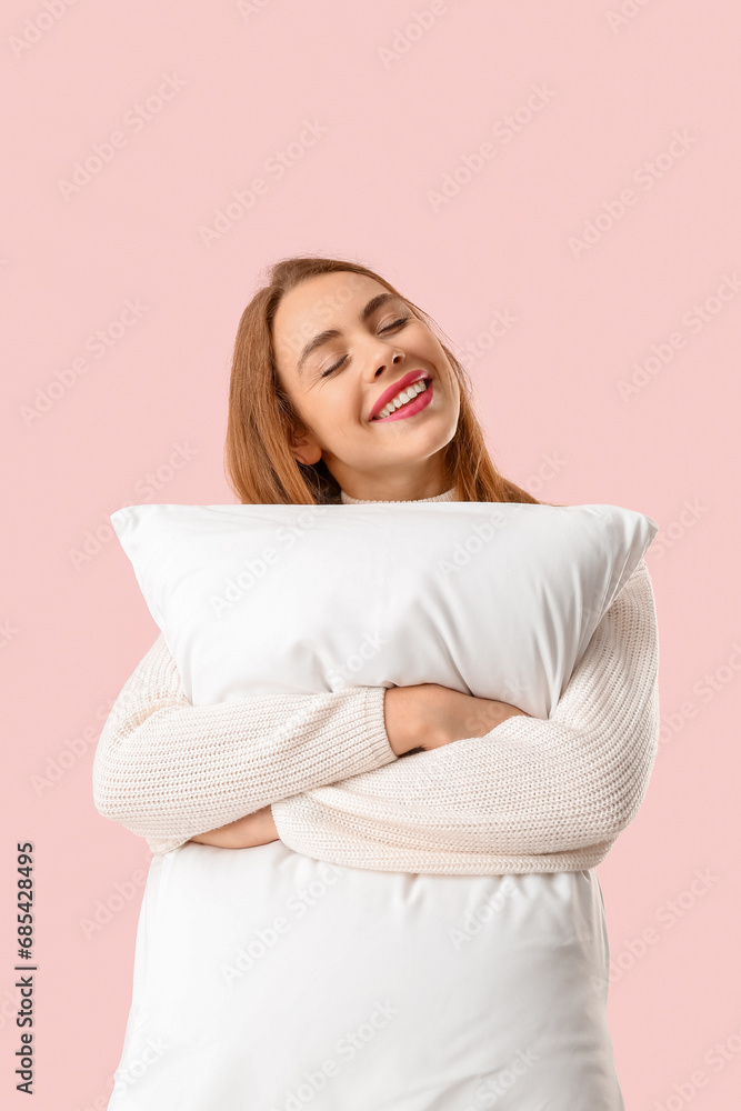 Beautiful young woman with white soft pillow on pink background