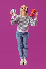 Wall Mural - Pretty young woman with geyser coffee makers on purple background